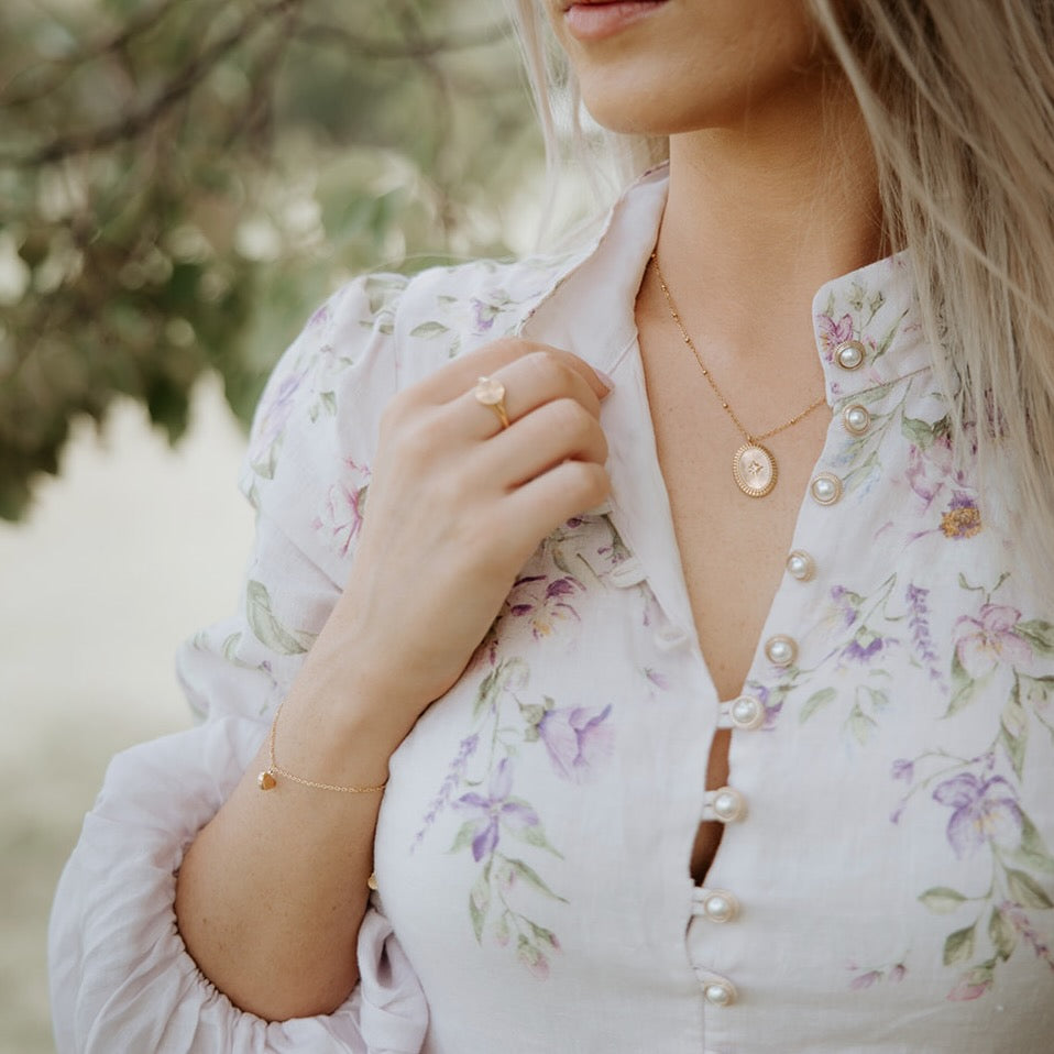 Woman wearing a floral dress with pearl buttons and jewelry outdoors