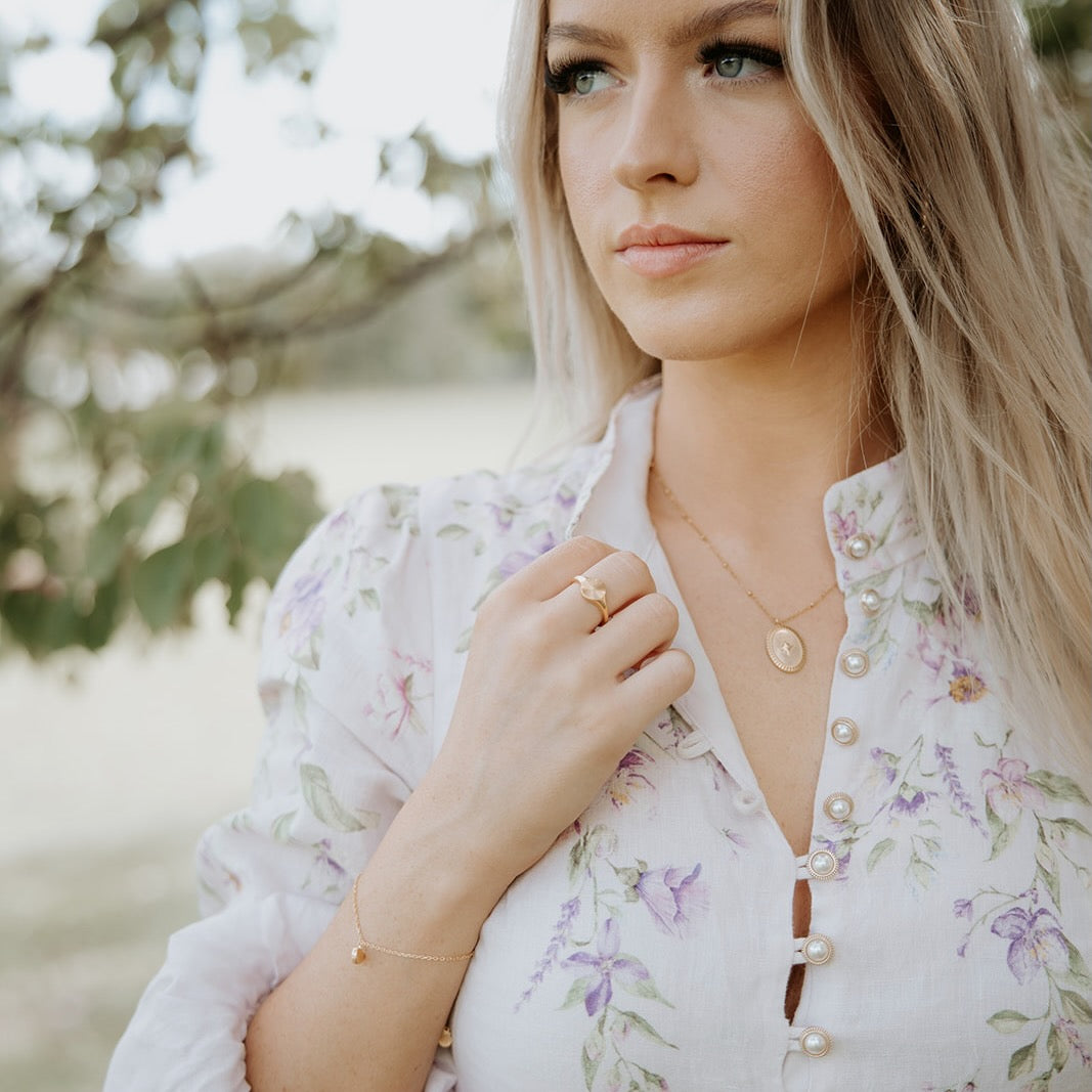 Woman wearing a floral blouse with jewelry outdoors